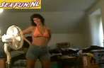 Sexy huisvrouw houdt een striptease voor videocamera
